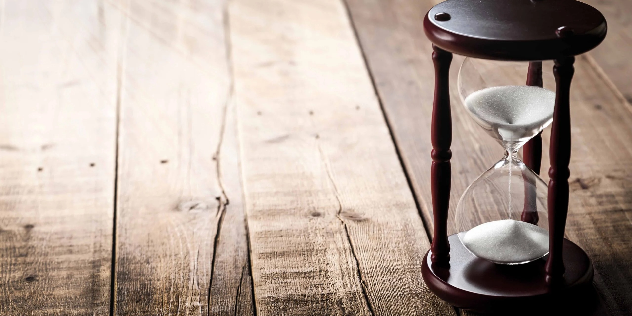 木目のテーブルの上に置かれた茶色い砂時計