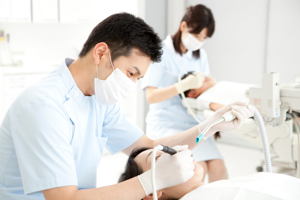 歯科医院で女性患者の治療をする男性歯科医師