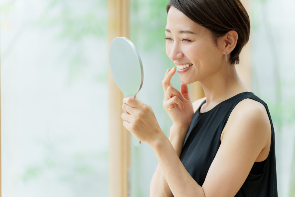 鏡で歯並びを確認して笑う女性
