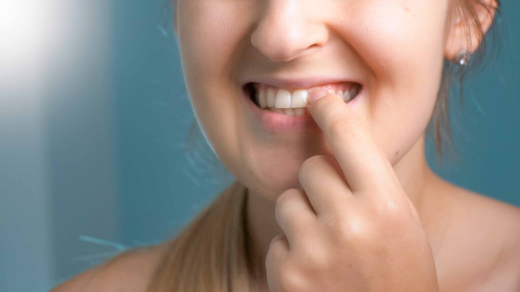 歯茎を指で触る女性