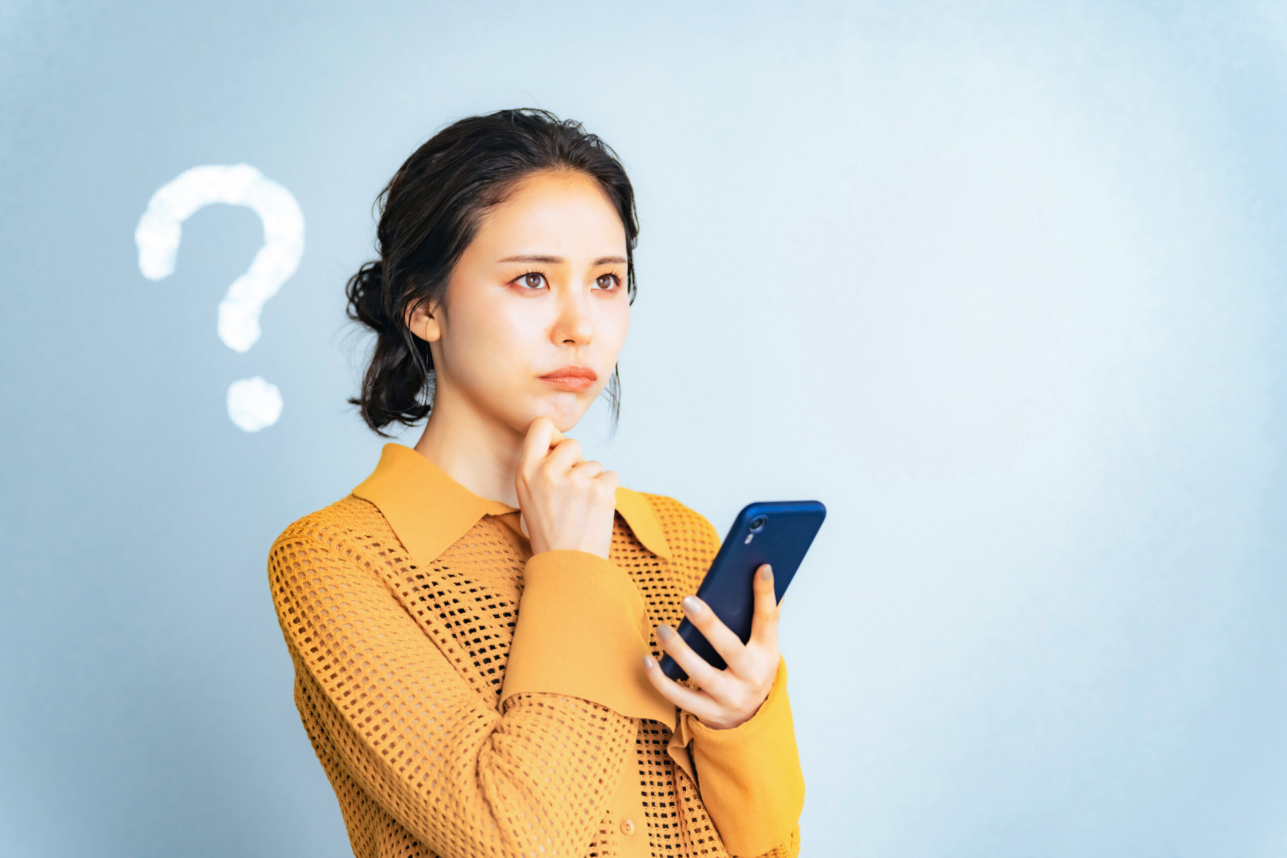 スマフォを持って悩む女性