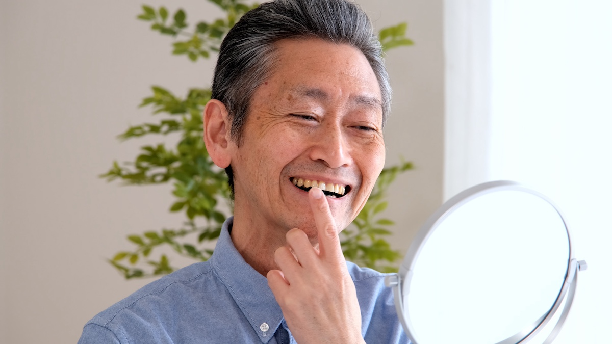 歯のセルフチェックをするシニア男性