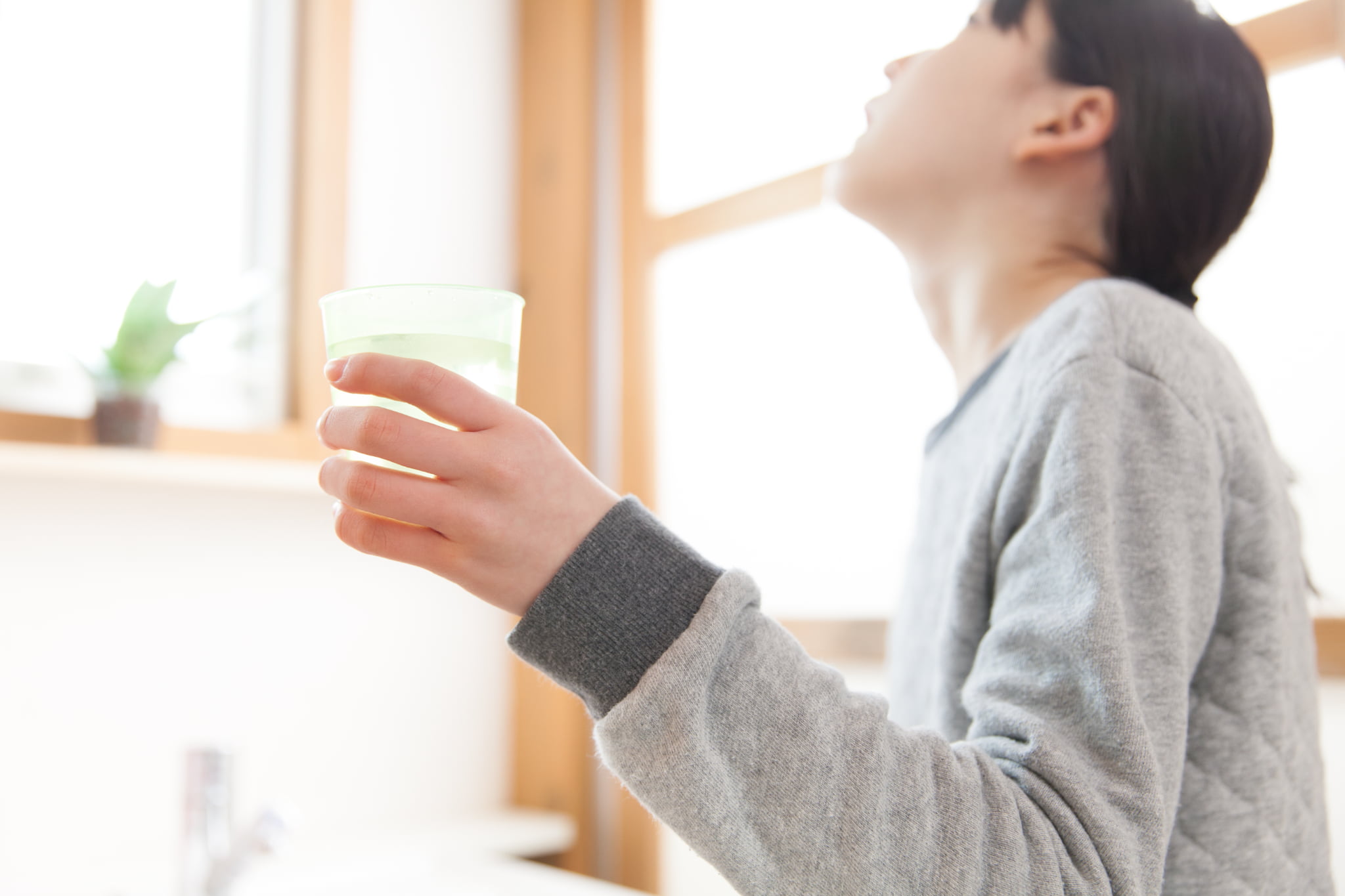 うがい薬を使用してうがいをする女性