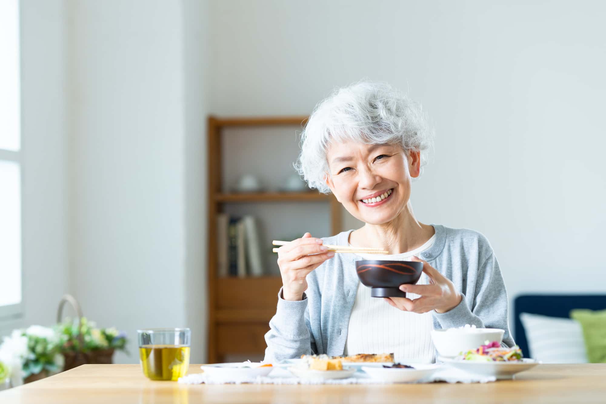 入れ歯の作製後も定期的に検診を受けて快適に食事をする女性