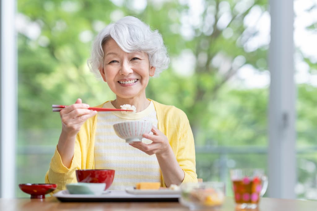 自分に合った入れ歯を装着し美味しく食事をいただく女性