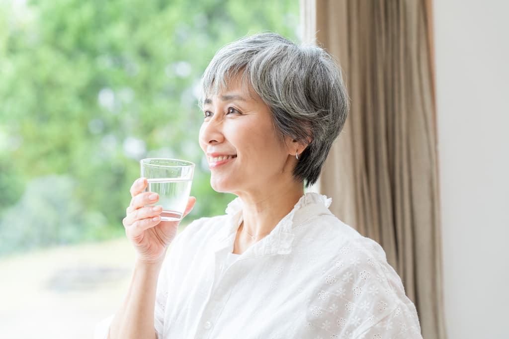 入れ歯を装着したときに口の中が乾くときの対処法として水分を摂る女性