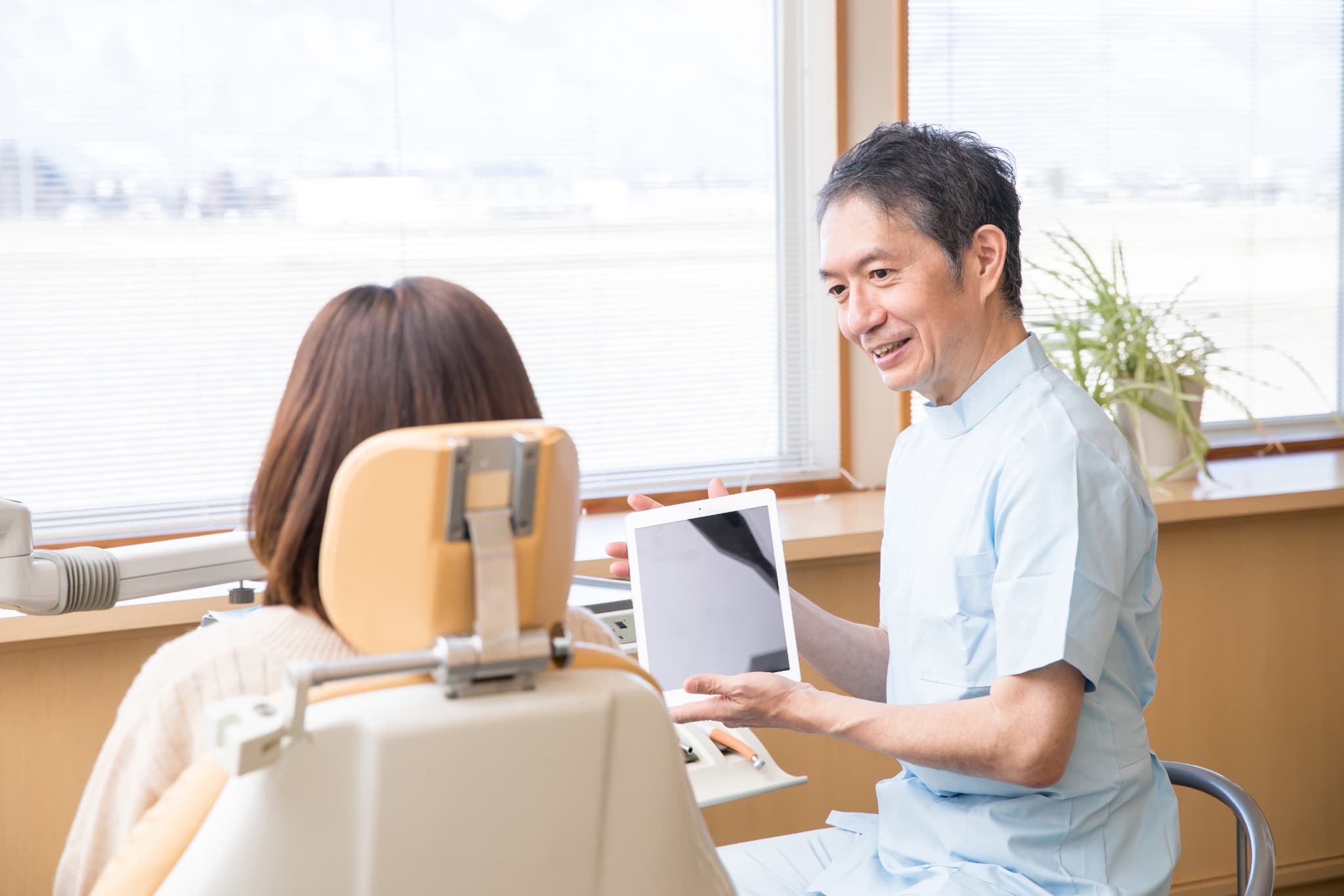 セラミックの歯が取れて受診した女性と説明する歯科医師