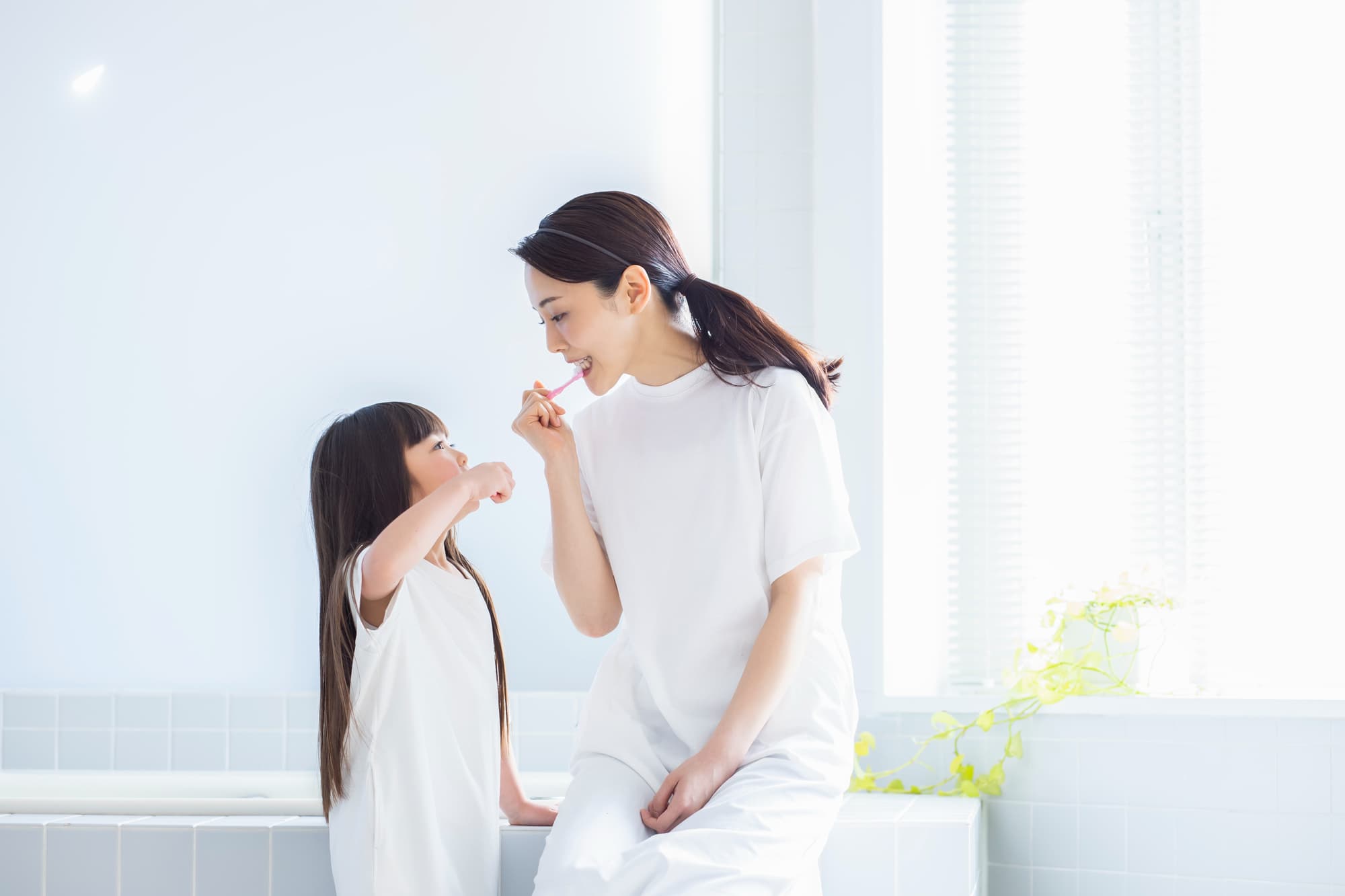 子どもに歯磨きのお手本を見せる母親