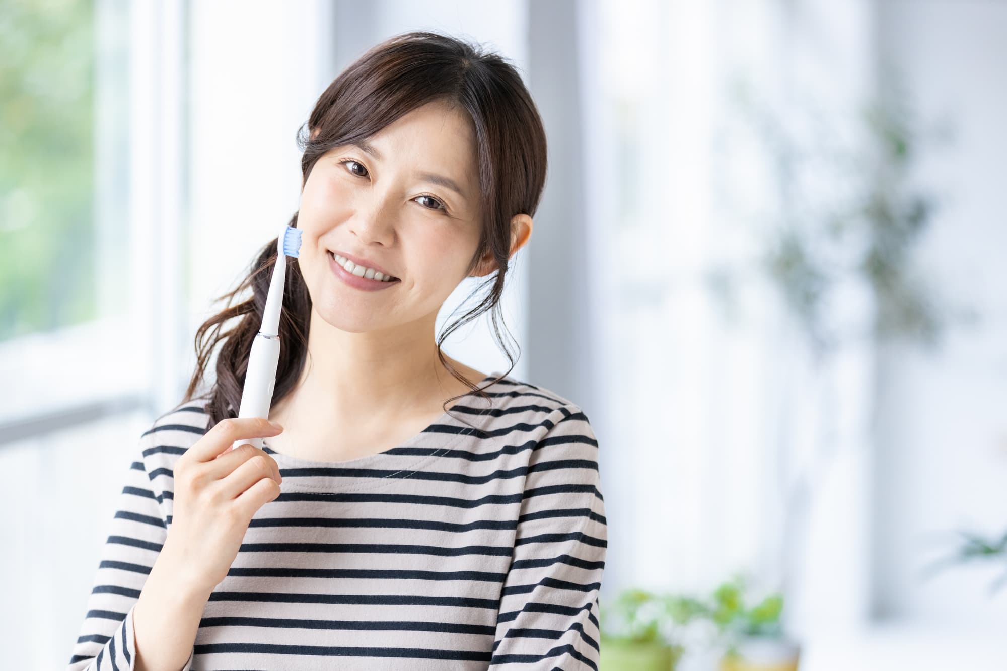 歯ブラシを持って笑顔を見せる女性