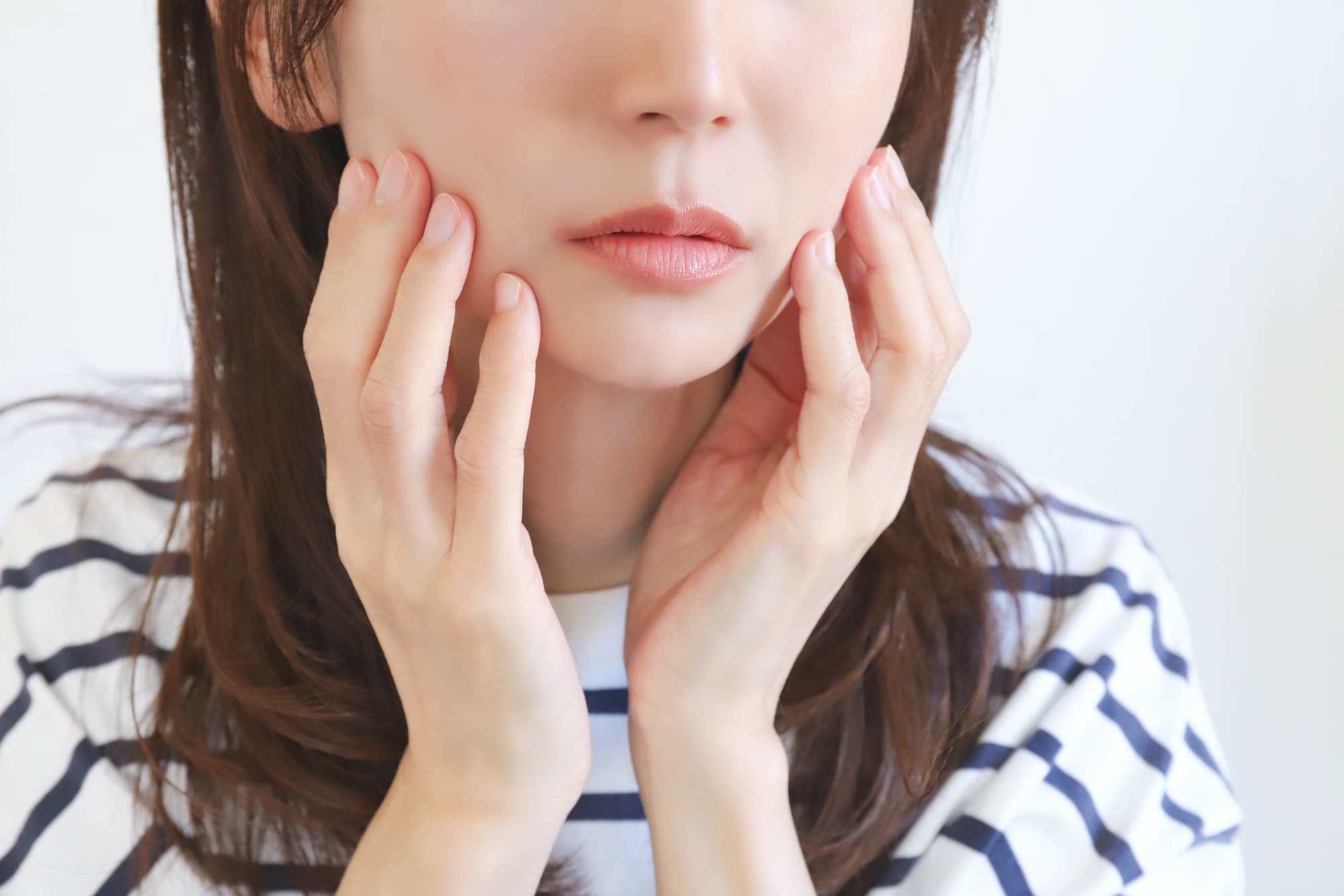 顎関節症で痛む顎をおさえる女性