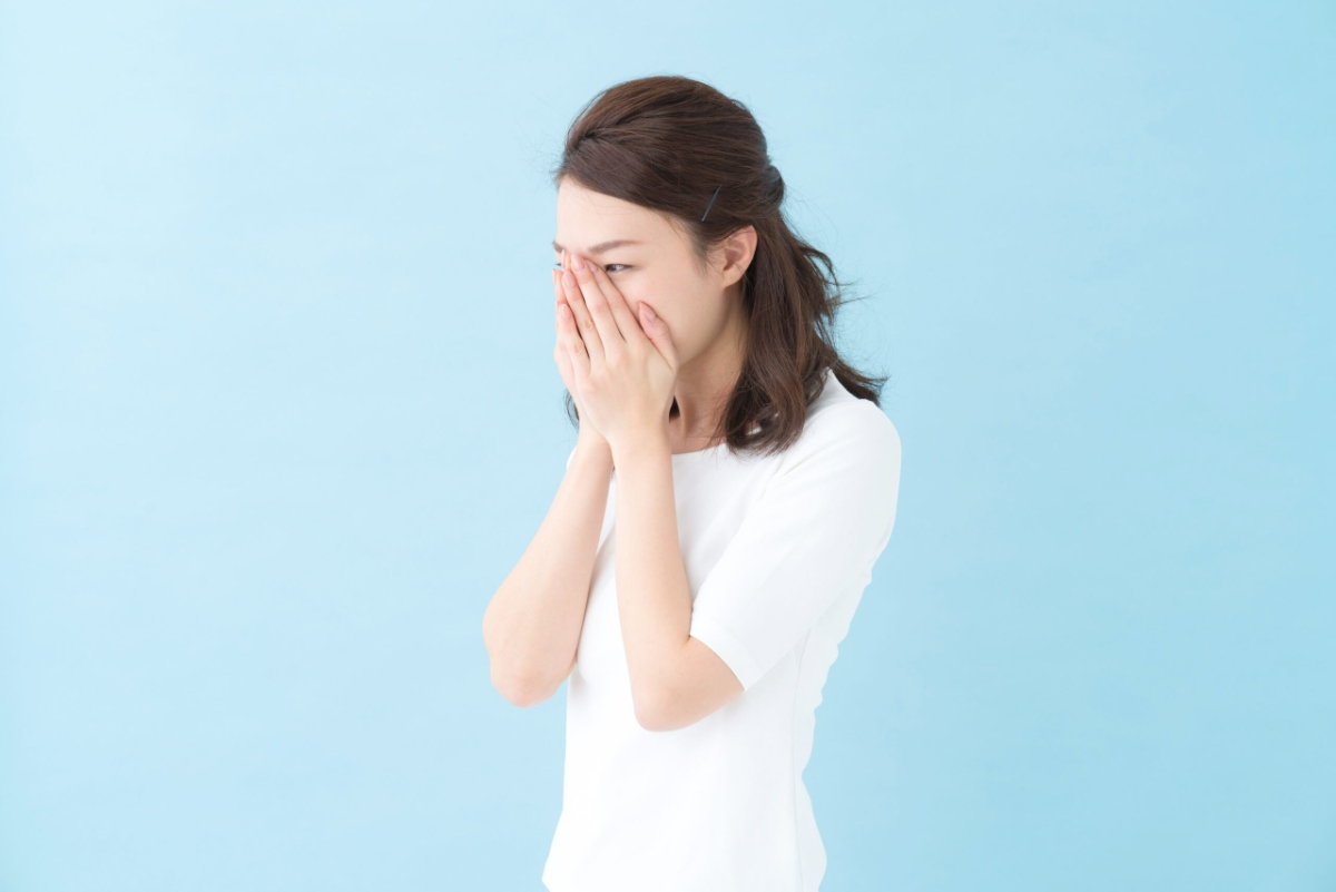 手で口を覆って口臭を確認している女性