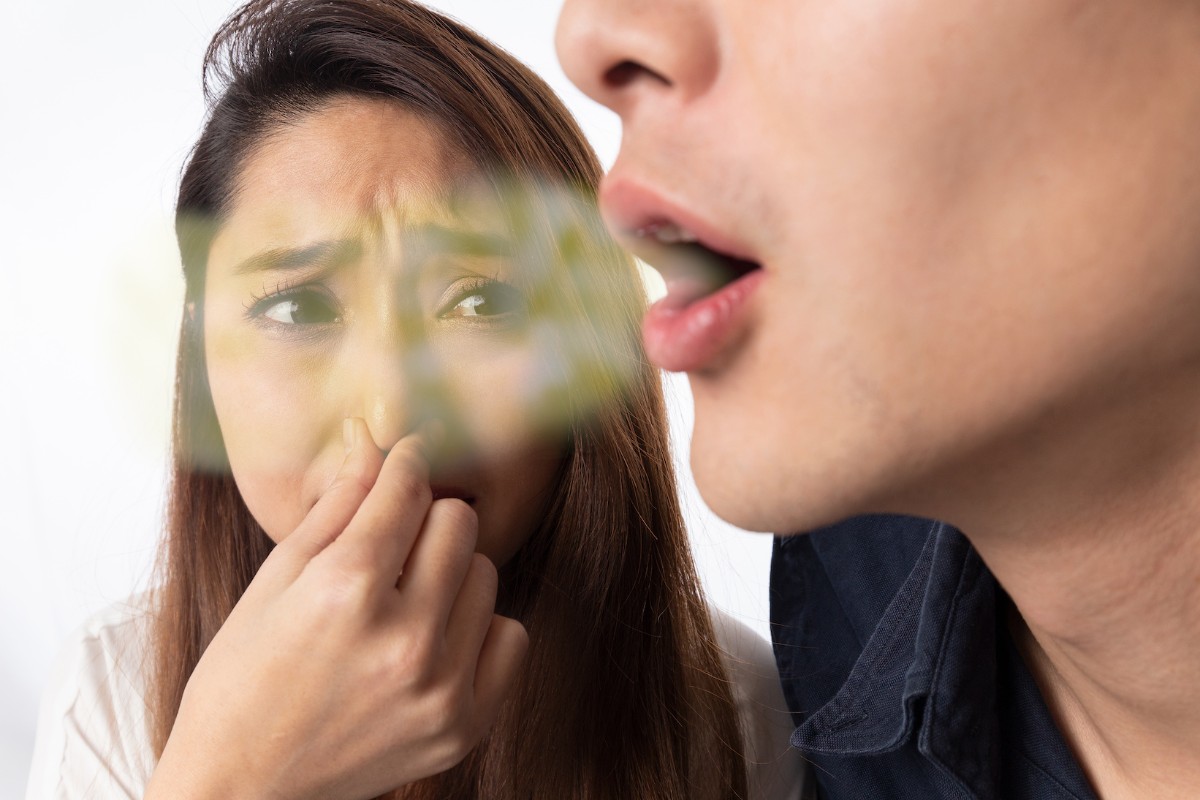 口臭に驚いて鼻をつまむ女性