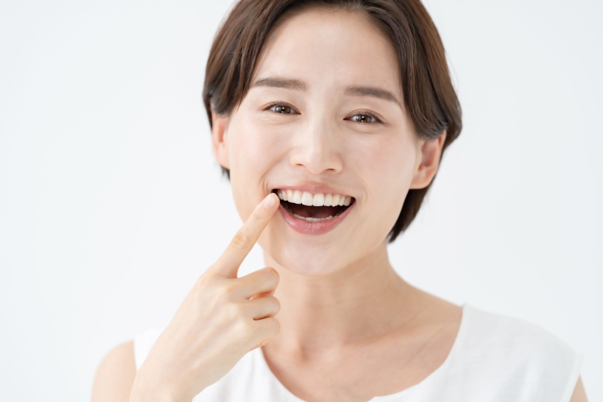 歯周病をケアして口臭がなくなった女性が口を指さして喜んでいるイメージ